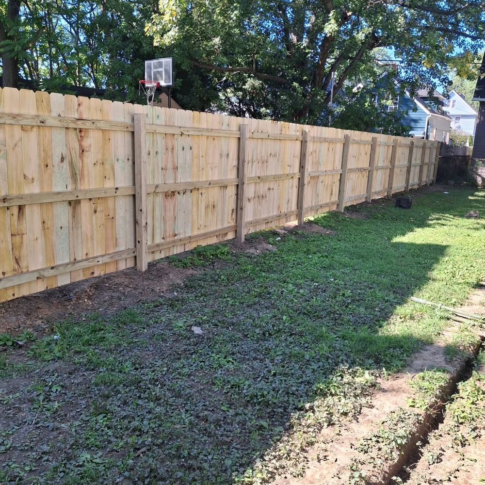 New pressure-treated wood privacy fence along a backyard