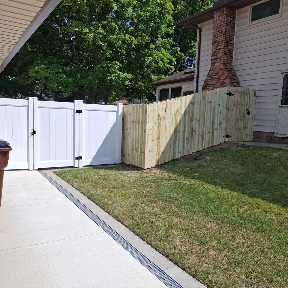 White double gate next to a new wood privacy fence by a driveway